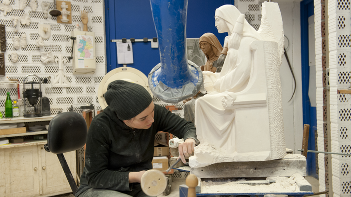 Eine Bildhauerin repariert eine Statue.
