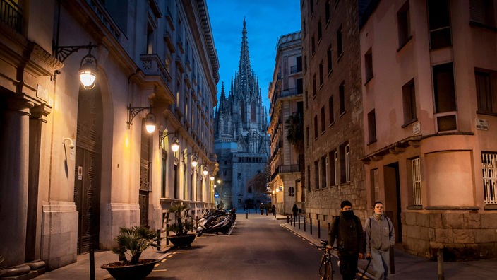 Im Vordergrund eine Gasse in Barcelona. Im Hintergrund die alte Kathedrale