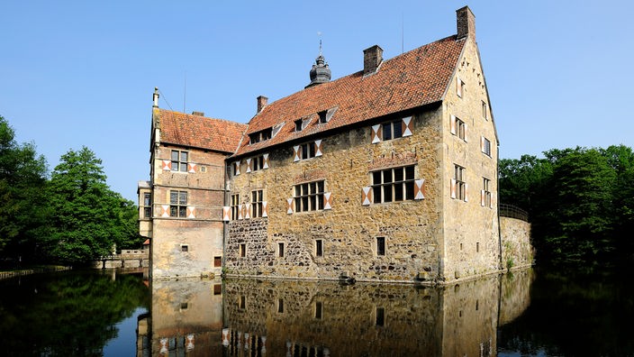 Im Wassergraben spiegelt sich die Seitenansicht der Burg Vischering 