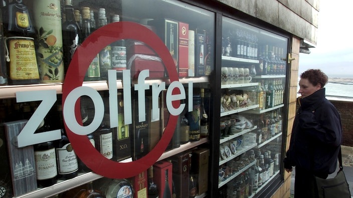 Das Foto zeigt den Blick durchs Schaufenster in einen Laden, in dem die Regale voll mit alkoholischen Getränken stehen. Auf die Glasscheibe ist ein roter Kreis gemalt; darüber steht in großen, weißen Buchstaben das Wort 'zollfrei'. | Bildquelle: wdr Das Foto zeigt den Blick durchs Schaufenster in einen Laden, in dem die Regale voll mit alkoholischen Getränken stehen. Auf die Glasscheibe ist ein roter Kreis gemalt; darüber steht in großen, weißen Buchstaben das Wort 'zollfrei'.