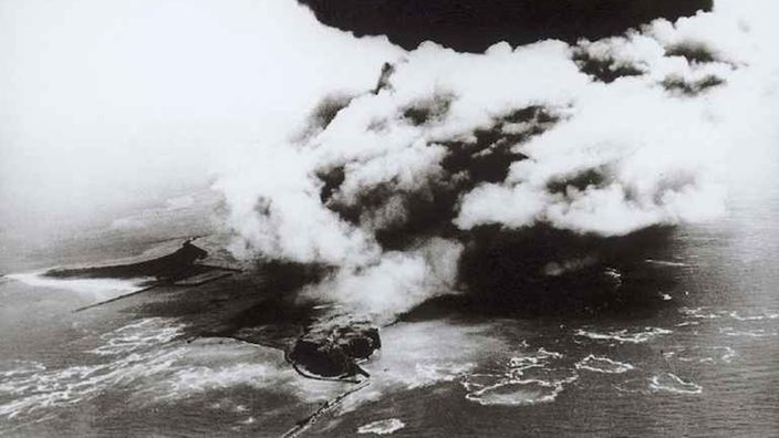 Das Schwarzweiß-Foto zeigt eine Luftaufnahme Helgolands mit riesigen Wolken über der Insel.