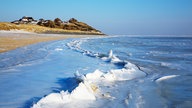 Reetdachhäuser auf dem Mellhorn über der zugefrorenen Blidselbucht auf Sylt.