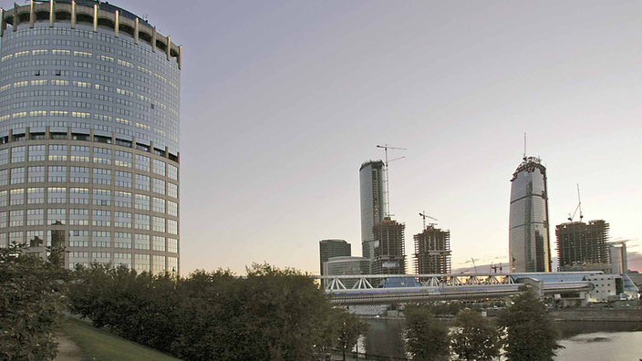 Moderner Wolkenkratzer mit Glasfront am Fluss Moskva. Im Hintergrund weitere moderne Hochhäuser.