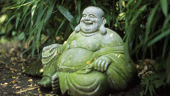 Eine steinerne Buddhafigur in einem Garten.