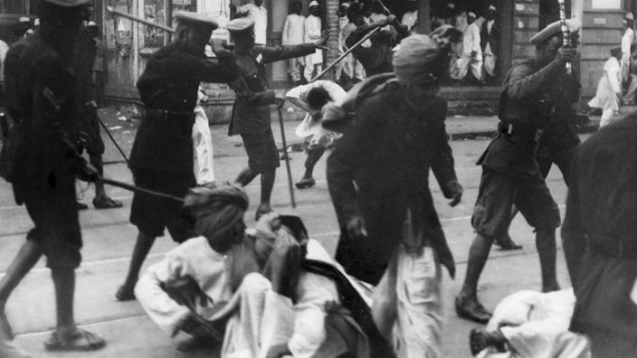 Indien 1939: Polizisten der britischen Kolonialbehörden prügeln mit Bambusstöcken auf indische Demonstranten ein