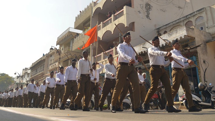 Männer mit Gewehren marschieren auf einer Straße in Indien | Bildquelle: picture alliance / Pacific Press Männer mit Gewehren marschieren auf einer Straße in Indien