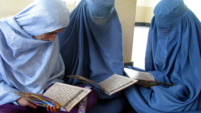 Drei verschleierte Mädchen lesen den Koran.