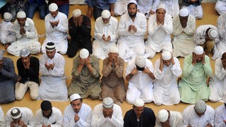 Eine Gruppe von indischen Männer sitzt zusammen ins Gebet versunken.