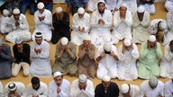 Eine Gruppe von indischen Männer sitzt zusammen ins Gebet versunken.