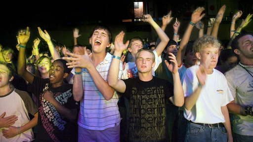 Jugendliche stehen betend, zum Teil mit geschlossenen Augen und erhobenen Händen, da.