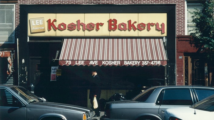 Über einem Ladenlokal mit Markise hängt ein Schild mit der Aufschrift 'Kosher Bakery', also 'Koschere Bäckerei'.