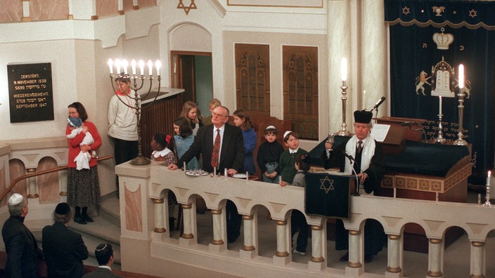 Gottesdienst in einer Synagoge. Ein Mann steht hinter einem Pult und spricht zur Gemeinde | Bildquelle: dpa Gottesdienst in einer Synagoge. Ein Mann steht hinter einem Pult und spricht zur Gemeinde