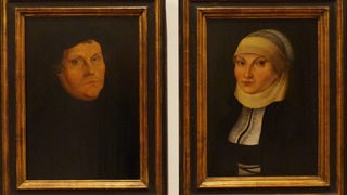 Porträtbilder von Martin und Katharina Luther hängen nebeneinander.