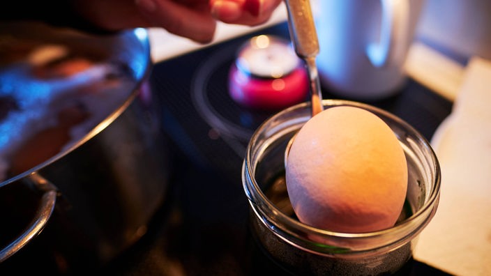 Ein Ei wird mit einem Löffel in Farbe getaucht