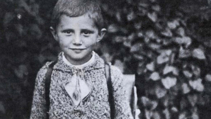 Schwarzweiß-Foto eines Jungen mit Schulranzen, der in die Kamera lächelt. | Bildquelle: afp Schwarzweiß-Foto eines Jungen mit Schulranzen, der in die Kamera lächelt.