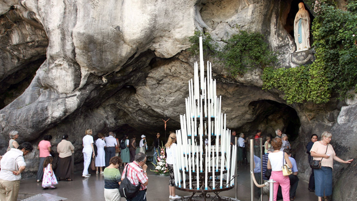 Betende Pilger vor der Quelle in Lourdes.
