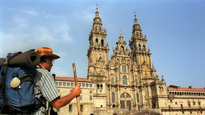 Ein Pilger steht vor der Kathedrale in Santiago de Compostela.
