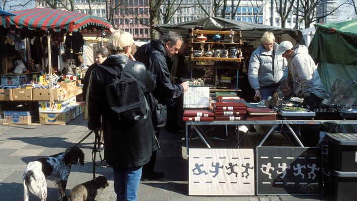 Zwei Händler auf dem Kölner Neumarkt verkaufen alte Briefmarkenalben, Kunden begutachten die Ware