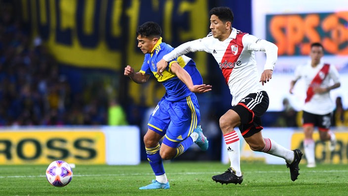 Ein Spieler von den Boca Juniors und einer von River Plate kämpfen auf dem Spielfeld um den Fußball