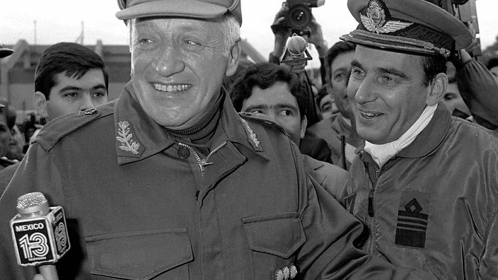 General Leopoldo Galtieri lacht bei einem Interview auf offener Straße in die Kamera.