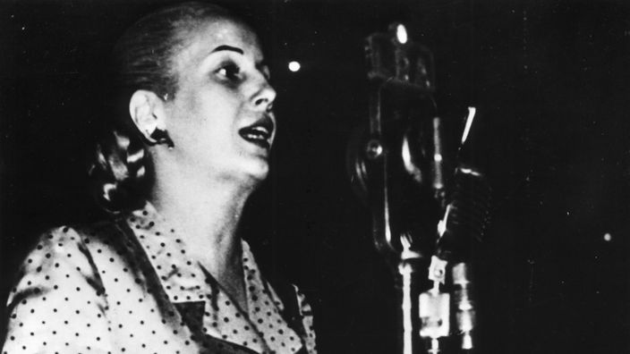 Evita Perón bei einer Wahlkampfveranstaltung. Sie ruft in ein Mikrofon.
