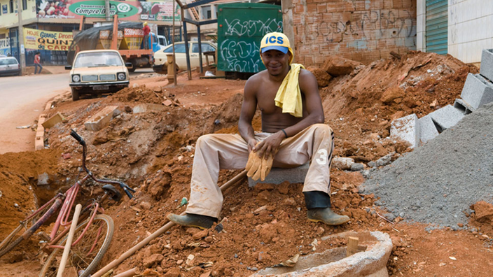 Ein Bauarbeiter sitzt auf einem Schutthaufen.