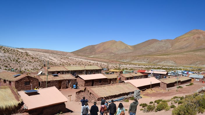 Eine Gruppe von Touristen geht zu einer Siedlung aus Lehmhäusern