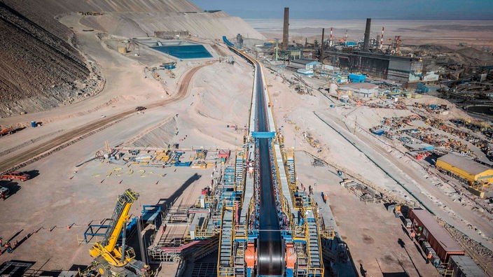 Die Mine Chuquicamata mit einem Förderband, Maschinen, einer Fabrik und Wasserbecken.