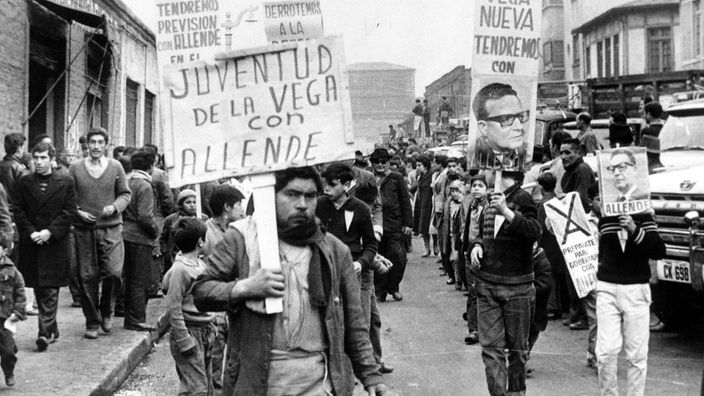 Mehrere Männer demonstrieren auf der Straße und zeigen Schilder mit der Aufschrift "Allende". 