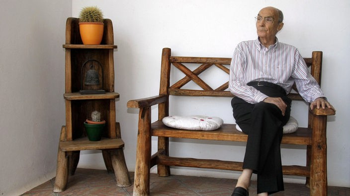 José Saramago posiert auf einer Bank sitzend bei einer Buchvorstellung in Madrid