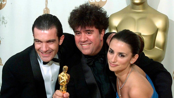 Almodóvar mit Penélope Cruz und Antonio Banderas, er hält seinen Oscar in der Hand und strahlt.