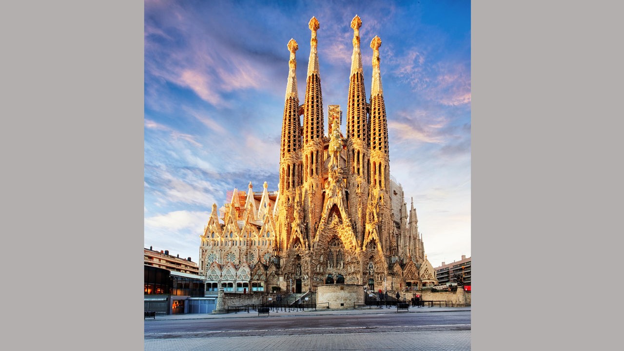 Die Fassade mit vielen kleinen und großen Türmen der Sagrada Familia im Abendlicht