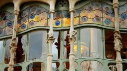 Detailaufnahme auf eine Fensterfront mit geschwungenen Formen, sowohl in der Fassade als auch im Glas der Fenster.
