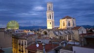 Blick über Dächer auf die abendlich angestrahlte Kirche von Figueres