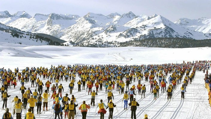 Blick auf Hunderte von Skilangläufern, die nebeneinander auf einem verschneiten Hochplateau ein Rennen ausführen.