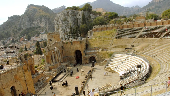 Seitlicher Blick von oben auf die Ränge eines gut erhaltenen antiken Amphitheaters.