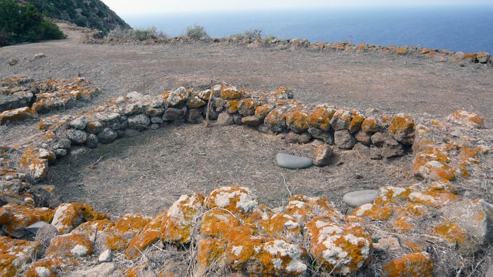 Blick über eine Ausgrabungsstätte, die aus ein paar runden Steinmauern besteht
