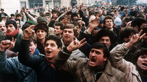 Eine große Volksmenge demonstriert mit erhobenen Händen gegen die Ceausescu-Diktatur.