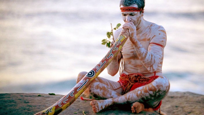 Aborigine bläst ein Digeridoo