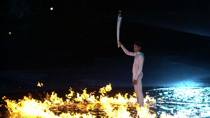 400-Meter-Läuferin Cathy Freeman entzündet das Olympische Feuer bei den Spielen in Sydney 2000. | Bildquelle: dpa 400-Meter-Läuferin Cathy Freeman entzündet das Olympische Feuer bei den Spielen in Sydney 2000.