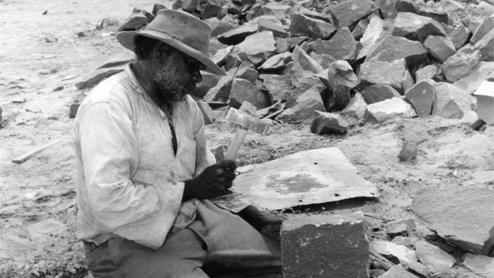 Ein Aboriginal-Mann arbeitet als Steinklopfer.