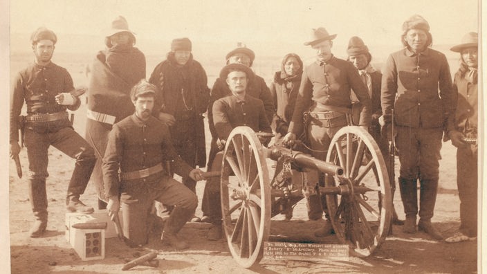 Gruppenbild von Schützen der US-Armee hinter einer Kanone nach dem Massaker