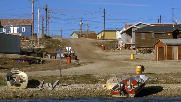 Inuit-Siedlung Cambridge Bay mit Holzhäusern und Motorboot.