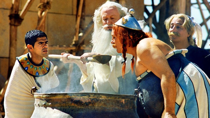 Das Bild zeigt eine Szene aus der Asterix-Realverfilmung 'Asterix und Obelix - Mission Kleopatra'. Obelix, gespielt von Gérard Depardieu, versucht vom Druiden Miraculix Zaubertrank zu bekommen. | Bildquelle: dpa Das Bild zeigt eine Szene aus der Asterix-Realverfilmung 'Asterix und Obelix - Mission Kleopatra'. Obelix, gespielt von Gérard Depardieu, versucht vom Druiden Miraculix Zaubertrank zu bekommen.