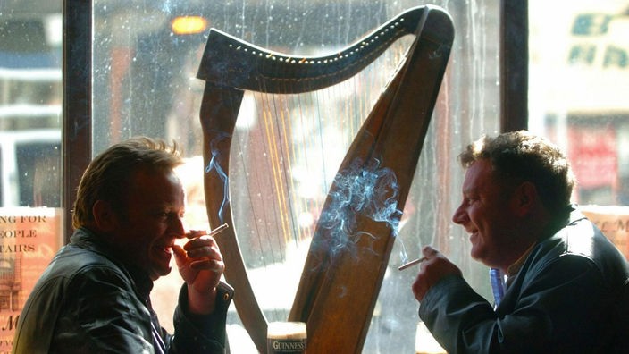 Zwei Männer sitzen in einem Pub vor einer irischen Harfe