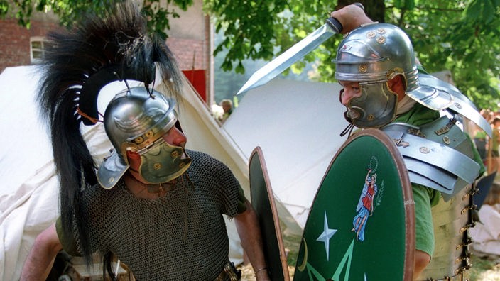 Zwei Männer in römischen Uniformen stellen eine Kampfszene nach