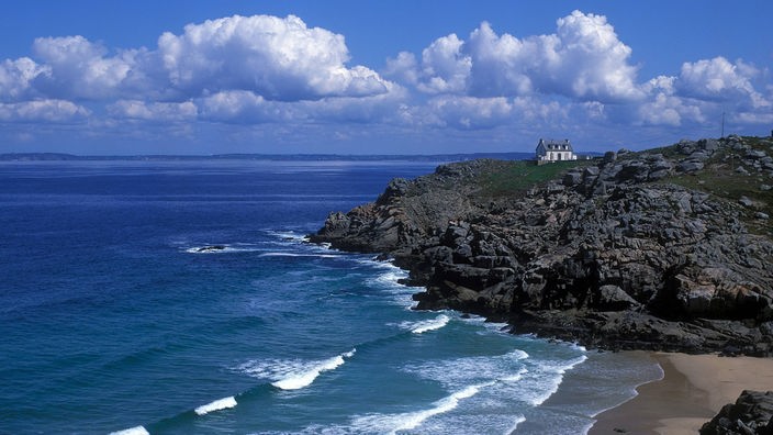 Felsige Küstenlandschaft der Bretagne. Auf einem Felsvorsprung steht ein einsames Haus.