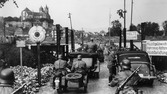 Schwarzweiß-Foto: Deutsche Soldaten überqueren den Rhein an einer Brücke