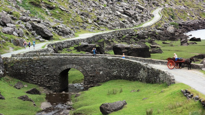 Eine malerische Steinbrücke führt in einem Tal über einen kleinen Bach