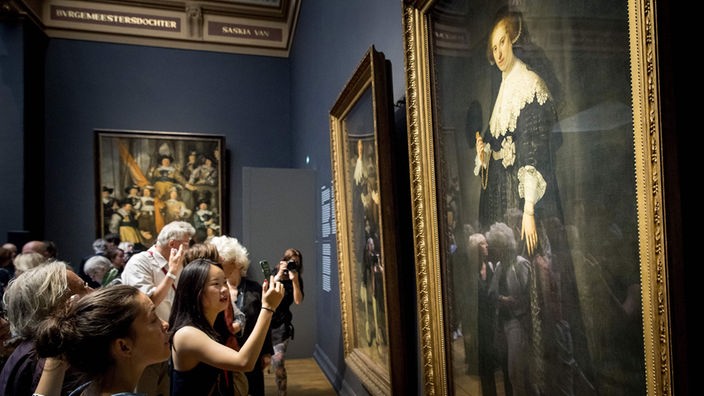 Besucher betrachten die ausgestellten Gemälde von Rembrandt im Amsterdamer Rijksmuseum.